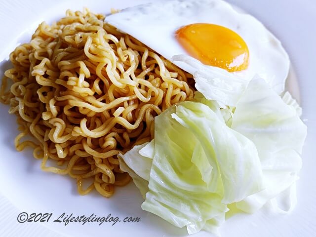 茹でたキャベツと目玉焼きを添えたIndomie（インドミー）のミーゴレンスペシャル