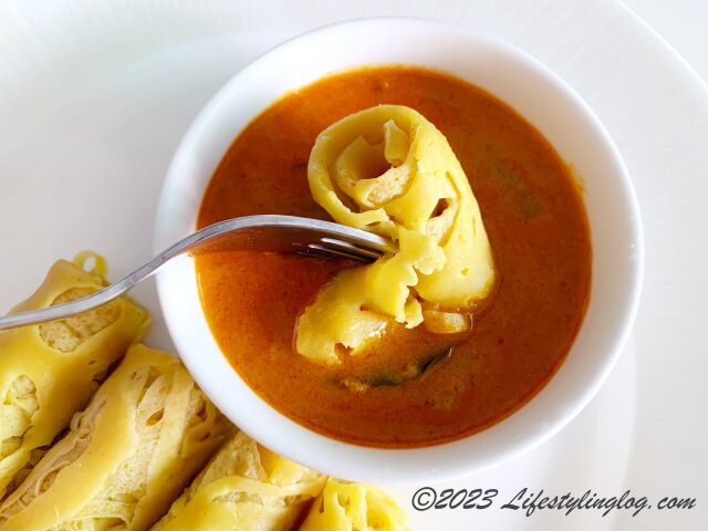 Roti Jala（ロティジャラ）をカレーにつけているところ